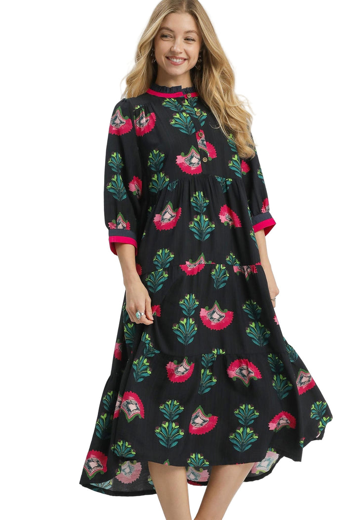 Woman wearing a black dress with colorful floral patterns on a white background