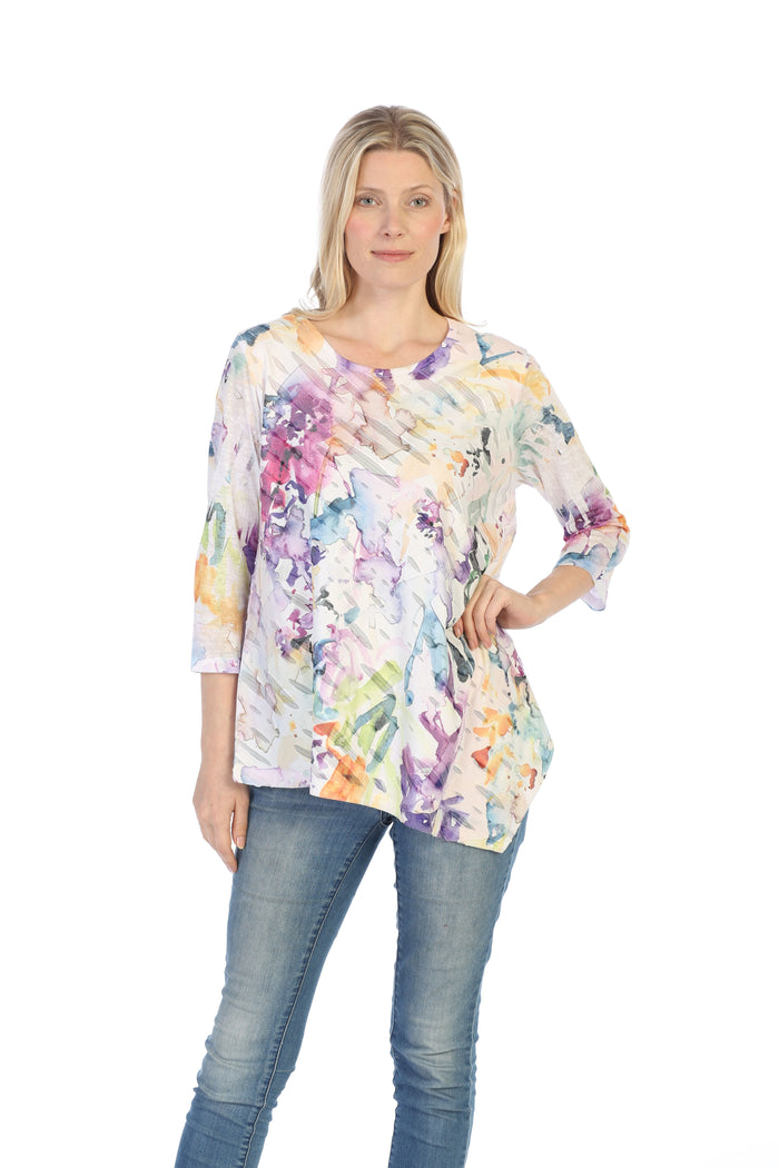 Woman wearing a colorful floral-patterned top and jeans on a white background