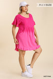 Woman wearing a hot pink dress with ruffled sleeves and bottom hem on a beige background.