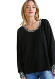 Woman wearing a black sweater with patterned cuffs and hem on a white background
