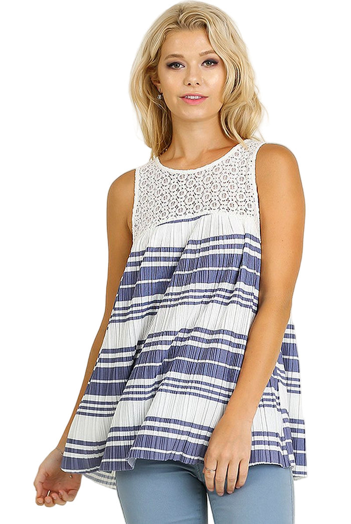 Woman wearing a sleeveless, striped dress with a white and blue pattern on a beige background.