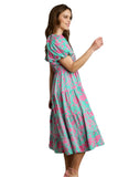 Woman wearing a floral dress with pink and green pattern on a gray background