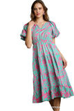 Woman wearing a green and pink floral dress against a gray background