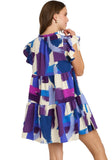 Woman wearing a colorful dress with abstract patterns on a plain background