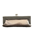 A metallic champagne clutch purse with a textured beaded frame and silver-tone kiss-lock clasp, resting on a gray carpet against a plain wall.