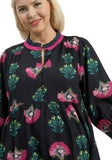 Woman wearing a black floral dress with pink accents on a white background