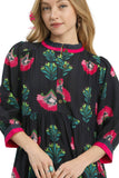 Woman wearing a black dress with colorful floral patterns on a white background