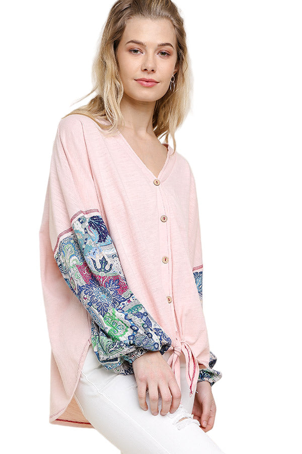 Woman wearing a pink blouse with colorful sleeves on a beige background