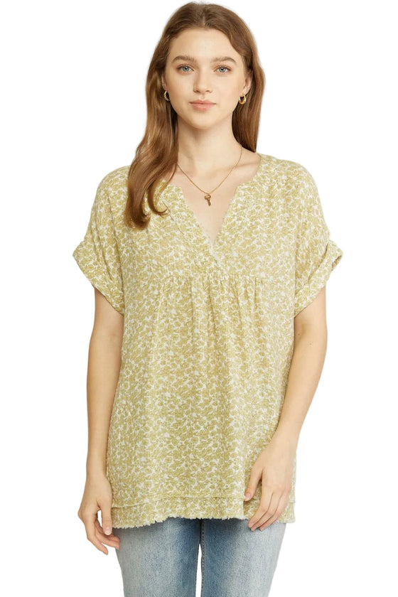 Woman wearing a yellow floral blouse against a white background