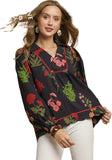 Woman wearing a black blouse with colorful floral embroidery on a beige background