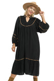 Woman wearing a black dress with gold trim and a beige hat on a white background