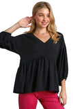 Woman wearing a black blouse with balloon sleeves against a gray background