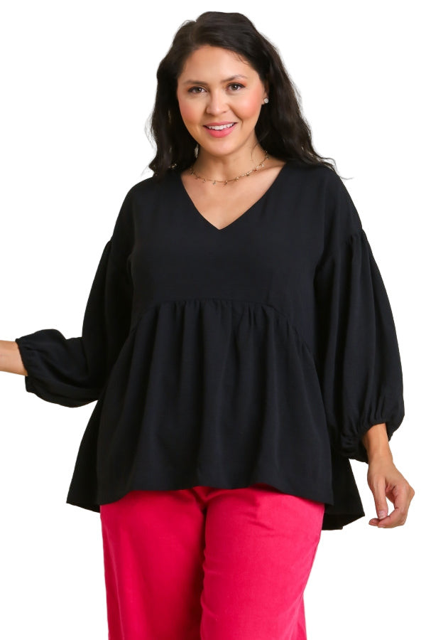 Woman wearing a black blouse and pink pants on a beige background
