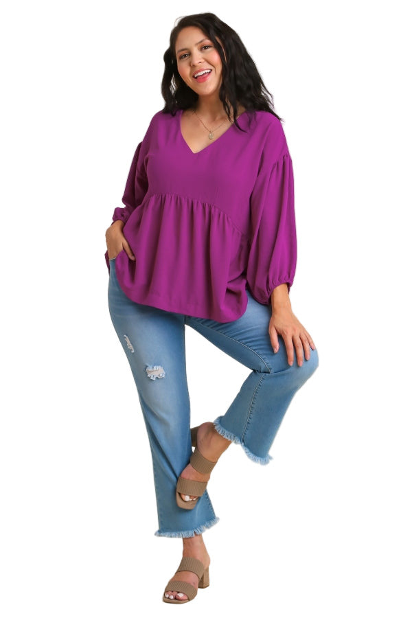 Woman wearing a purple blouse and blue jeans on a beige background