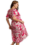 Woman wearing a hot pink and white floral dress against a gray background