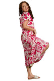 Woman wearing a plus size pink and white floral dress against a gray background