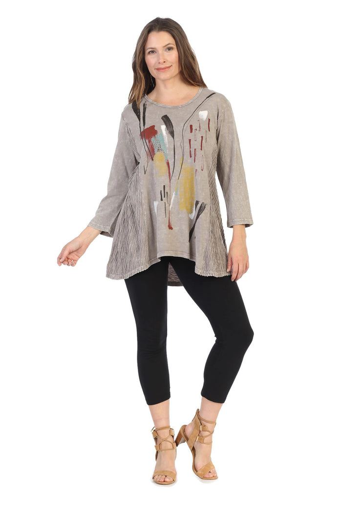 Woman wearing a long-sleeve top with abstract design and black leggings on a white background