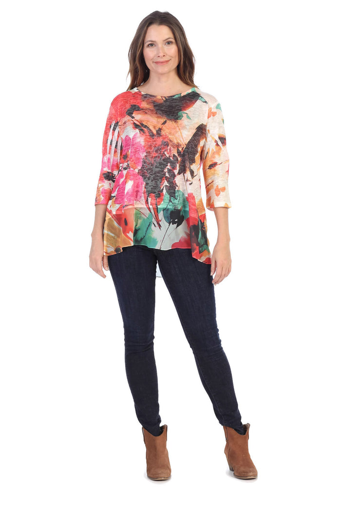 Woman wearing a colorful floral top and dark jeans on a white background