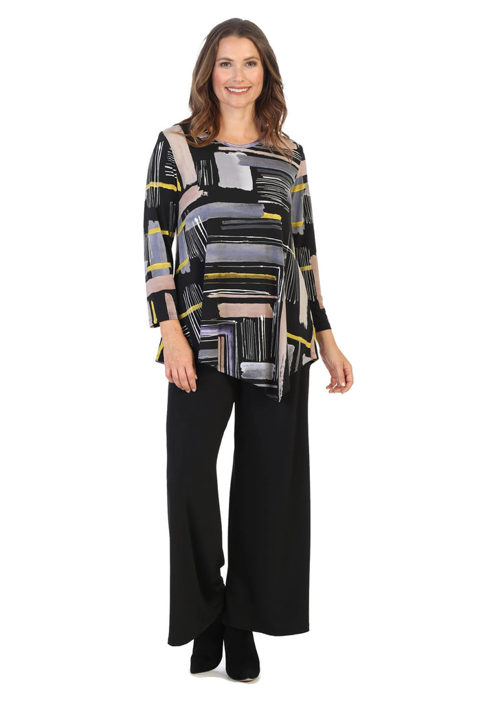 Woman wearing a patterned top and black pants on a white background