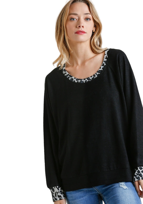Woman wearing a black sweater with patterned cuffs and hem on a white background